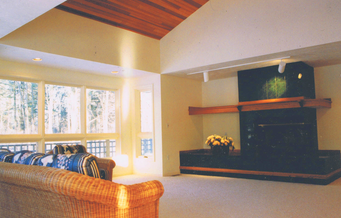 Living room of the Bourque Road Residence in Boston, Massachusetts, featuring a vaulted wood ceiling, floor-to-ceiling windows, a contemporary fireplace with a floating wood mantel, and abundant natural light.