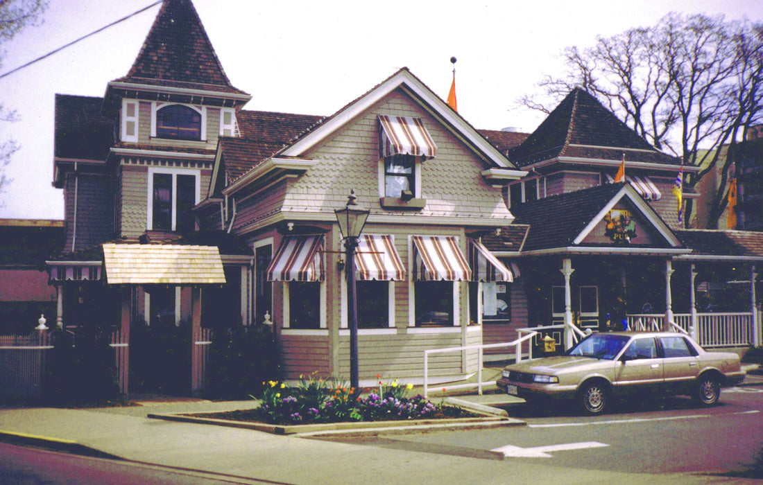 Completed Christies Carriage House Pub in Victoria, British Columbia, featuring the restored Queen Anne heritage residence with a pub addition, wraparound porch, decorative woodwork, and historically inspired architectural details.