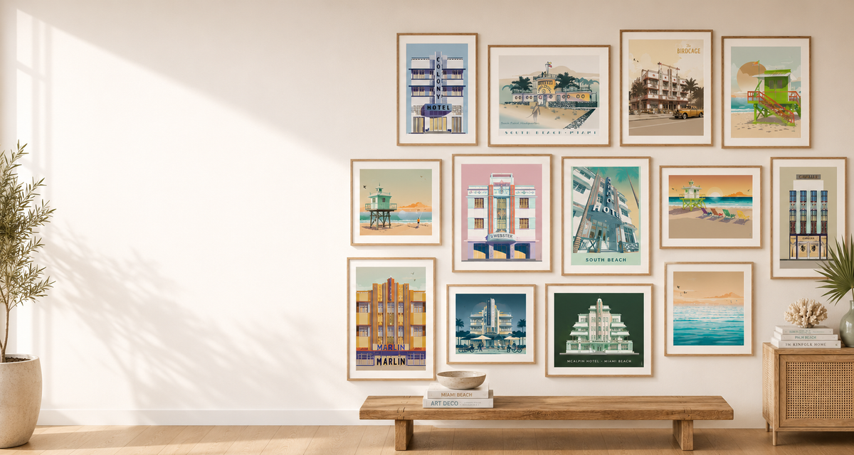 A gallery wall display of twelve framed vintage-style travel art prints featuring coastal buildings, boats, and beach scenes, arranged above a wooden bench in a bright, modern room.