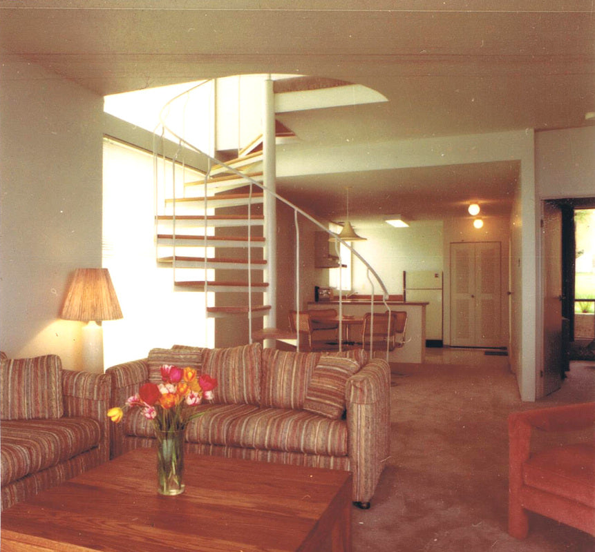 Interior of a condominium at the Inn of the Sea Resort in Ladysmith, British Columbia, featuring an open-concept living area, spiral staircase, vaulted ceiling, and contemporary waterfront resort design.